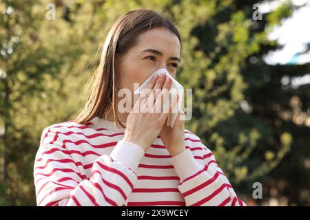 Donna con tovagliolo che soffre di allergia stagionale all'aperto Foto Stock