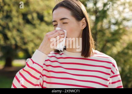 Donna con tovagliolo che soffre di allergia stagionale all'aperto Foto Stock