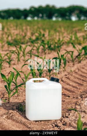 Barattolo bianco bianco bianco per la raccolta di erbicidi nel campo delle piantine di mais al tramonto primaverile, con messa a fuoco selettiva Foto Stock