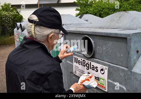 Eine Frau entsorgt ihr Altglas im container. Weissglas Recycling, Altglascontainer a einem Wohngebiet. Entsorgung von Weissglas, Grünglas und Braunglas *** Una donna smaltisce il suo vetro usato nel contenitore di riciclaggio in vetro bianco, contenitore di vetro usato in una zona residenziale smaltimento di vetro bianco, vetro verde e vetro marrone Foto Stock