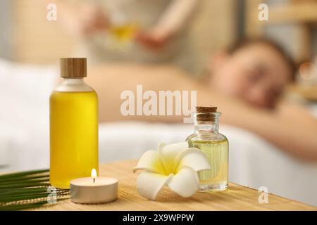 Aromaterapia. Donna che riceve un massaggio alla schiena nel salone spa, si concentra su bottiglie di oli essenziali e candele accese Foto Stock