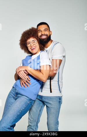 Un uomo e una donna afroamericana vestiti con stile posano per un'immagine su sfondo grigio, che mostra la loro amicizia. Foto Stock