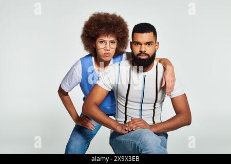 Un uomo e una donna afroamericani vestiti con abiti eleganti posano per una foto su uno sfondo grigio. Foto Stock