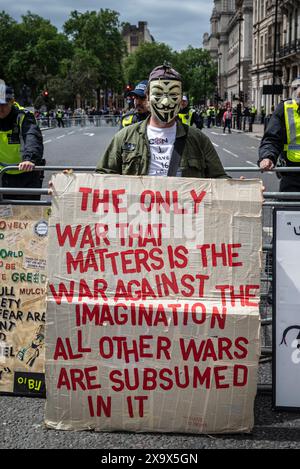 Uomo che indossa la maschera di Guy Fawkes e tiene il cartello che dice che la guerra all'immaginazione è la guerra più pericolosa, Londra, Inghilterra, Regno Unito Foto Stock