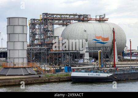 Una chiatta ormeggiata accanto ai serbatoi di stoccaggio del gas naturale liquefatto nel porto di Anversa, nelle Fiandre, in Belgio Foto Stock