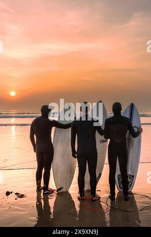 Uno spettacolare tramonto che fiorisce i surfisti sulla Fistral Beach alla fine di uno dei giorni più caldi dell'anno a Newquay in Cornovaglia. Foto Stock