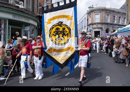 Il banner per il Golowan Festival che conduce la colorata processione del Mazey Day attraverso il centro di Penzance Town in Cornovaglia, in Inghilterra, nel Regno Unito. Foto Stock