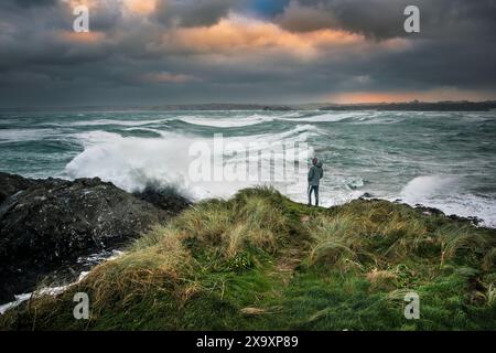 Una persona in piedi su Towan Head che guarda il tempo selvaggio e il mare selvaggio nella baia di Newquay causato da Storm Arwen in Cornovaglia. Foto Stock