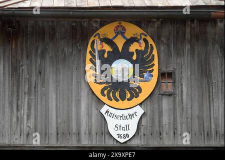 Narzissenfest a Grundlsee am Grundlsee im Steirischen Salzkammergut, am 02.06.2024. DAS Bild zeigt den kaiserlichen Doppeladler mit der drunterliegenden Beschriftung: Kaiserlicher Stall 1680 an einem Holzhaus am Ortseingang von Grundlsee 2024 - Narzissenfest in Rundlsee am Grundlsee im Steirischen Salzkammergut, am 02.06.2024. *** Daffodil festival a Grundlsee am Grundlsee nel Salzkammergut Stiriano, il 02 06 2024 l'immagine mostra l'aquila imperiale a doppia testa con l'iscrizione Kaiserlicher Stall 1680 sotto su una casa di legno all'ingresso del Grundlsee 2024 Daffodil festival i Foto Stock