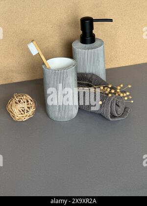 Bagno minimalista con portaspazzolino e dispenser di sapone su superficie grigia Foto Stock