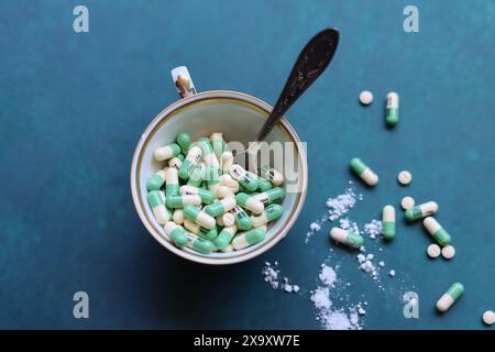 Pillole, compresse e capsule farmaceutiche su sfondo blu. Pillole in tazza di ceramica bianca su un tavolo. Spazio per il testo. Medicina, droga Foto Stock