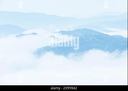 Una vista serena e accattivante di una catena montuosa avvolta dalla nebbia in Norvegia. Le dolci colline e le morbide nuvole eteree creano un senso di tranquillità Foto Stock