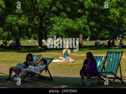 Le persone godono di un periodo di caldo, mentre alcune persone prendono il sole e altre evitano il sole diretto a Hyde Park, Londra. Foto Stock