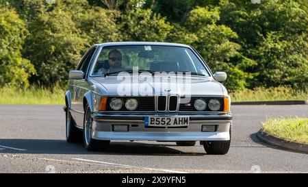 Stony Stratford, Regno Unito - 2 giugno 2024: BMW M635 csi serie 6 argento 1985 che guida su una strada di campagna britannica Foto Stock