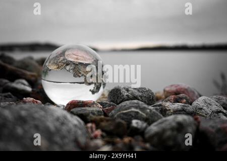 Primo piano di una sfera di cristallo e pietre sulla spiaggia contro il cielo Foto Stock