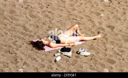St Andrews, Fife, Scozia, Regno Unito. 3 giugno 2024. Meteo nel Regno Unito: St Andrews a Fife, Scozia, sta vivendo una meravigliosa ondata di caldo all'inizio dell'estate, con temperature che raggiungono i 25°C.. Sia la gente del posto che i turisti trascorrono la giornata alla spiaggia del castello di St Andrews prendendo il sole e nuotando nel fresco Mare del Nord mentre si gode il caldo clima di giugno. Crediti: Dundee Photographics/Alamy Live News Foto Stock