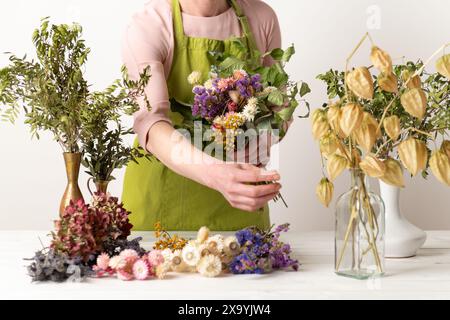 Fiori secchi. Fiorista donna che organizza fiori secchi in un bellissimo bouquet. Floristeria sostenibile. Creazione di decorazioni per la casa con fiori secchi. Foto Stock