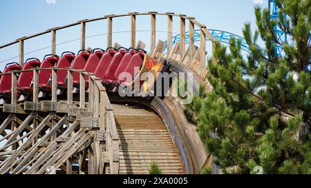 Rust, Germania - 26 marzo 2024: Treno delle montagne russe di legno "Wodan Timburcoaster" nel parco a tema "Europa-Park" durante un viaggio vuoto su un soleggiato Foto Stock