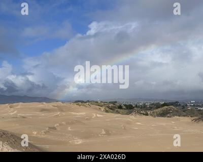 Un arcobaleno sopra una duna sgombra nel paesaggio desertico Foto Stock