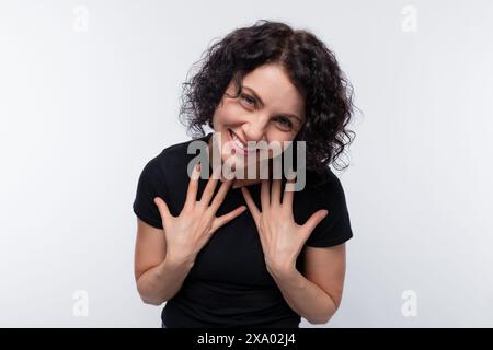 Donna bruna adulta con capelli ricci e una maglietta nera Foto Stock