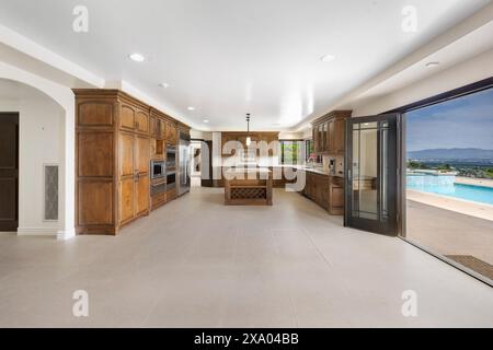 Un ampio soggiorno con porte aperte che conducono ad una piscina esterna in California Foto Stock