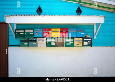 Un mucchio di cassette postali colorate sullo scaffale a parete Foto Stock