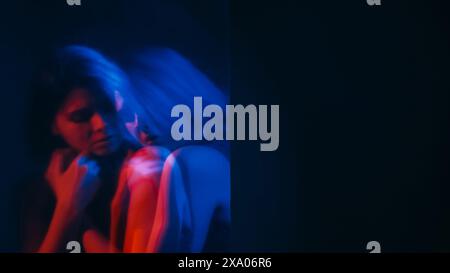 Donna vulnerabile. Silhouette sfocata. Depressione femminile triste solitaria copertura mentale insicura rosso neon blu doppia esposizione spazio vuoto fuori fuoco. Foto Stock