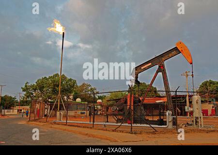 Cabimas, Zulia. Venezuela. 18-03-2015. Una pompa dell'olio è visibile accanto a un camino a gas in un quartiere di Cabimas. Foto di: Jose Bula. Foto Stock