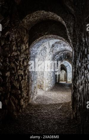 Un antico tunnel di pietra che conduce ad una porta piena di luce Foto Stock