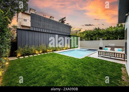 Cortile sul retro con piscina e area recintata con lussureggiante erba verde. Foto Stock