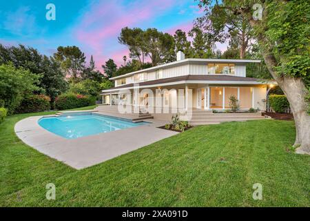 Una vista su un ampio cortile sul retro con una grande piscina e patio Foto Stock