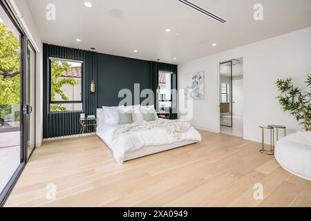 Interno di una camera da letto con pavimenti in legno e finestre spaziose Foto Stock