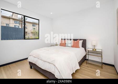 Letto grande con cuscini bianchi e arancioni in camera da letto Foto Stock