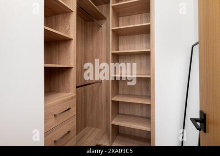 Cabina armadio in legno con scaffali vuoti e una libreria Foto Stock