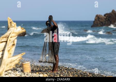 Uomo con una rete in piedi su una spiaggia sabbiosa a riva Foto Stock