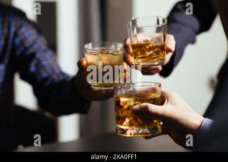 Un gruppo di uomini d'affari ha tenuto insieme gli occhiali di brandy per applaudire gli occhiali di brandy dopo aver concluso le trattative sulle imprese e aver raggiunto un sati Foto Stock