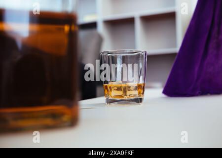 il bicchiere di brandy che viene tenuto sul tavolo in ufficio è un bicchiere di brandy che gli uomini d'affari spesso bevono dopo l'orario di lavoro per lasciare che l'alcol li aiuti re Foto Stock