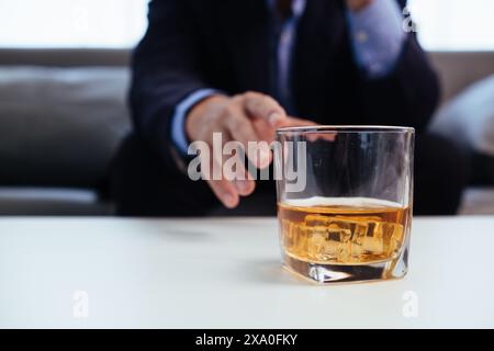 il bicchiere di brandy che viene tenuto sul tavolo in ufficio è un bicchiere di brandy che gli uomini d'affari spesso bevono dopo l'orario di lavoro per lasciare che l'alcol li aiuti re Foto Stock