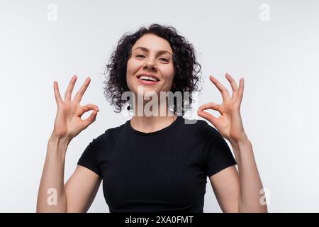 Allegra bruna con acconciatura riccia che indossa una t-shirt essenziale Foto Stock