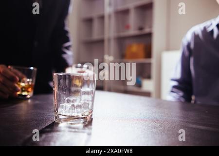 il bicchiere di brandy che viene tenuto sul tavolo in ufficio è un bicchiere di brandy che gli uomini d'affari spesso bevono dopo l'orario di lavoro per lasciare che l'alcol li aiuti re Foto Stock