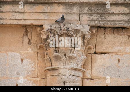 Una statua realistica di animali in pietra appare appollaiata in cima a un alto pilastro di mattoni, adagiato sullo sfondo di un muro di mattoni rossi Foto Stock