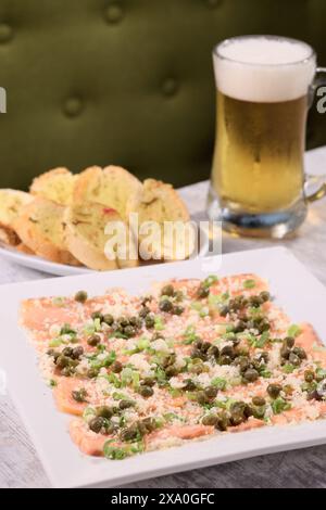 Un piatto di pesce e una birra sul tavolo del ristorante Foto Stock