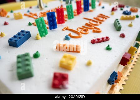 La torta di compleanno ha glassa bianca e decorata con mattoni colorati come candele. Foto Stock