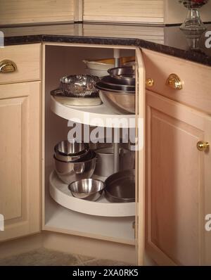 Armadietto ad angolo con ripiani pigri Susan per riporre ciotole e utensili da cucina in acciaio inossidabile, soluzione di stoccaggio salvaspazio in interni moderni Foto Stock