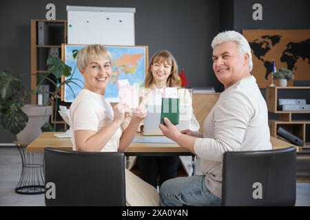 Coppia matura con passaporti seduti nell'agenzia di viaggi Foto Stock