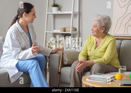 Donna anziana con fisioterapista che parla a casa Foto Stock