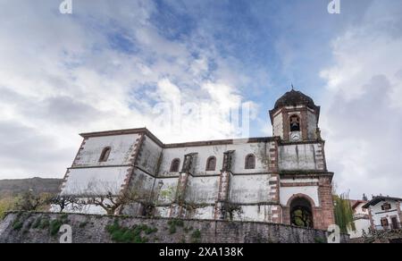 Una grande chiesa bianca con campanile in una giornata autunnale parzialmente nuvolosa, situata nel villaggio delle streghe a Zurragamurdi nella valle del Baztan. Foto Stock