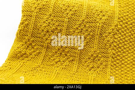 Foto ravvicinata di una texture coperta in lana gialla, dettagli di una maglia a diamante e motivo a maglia purl Foto Stock