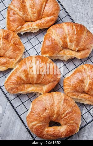 I croissant appena sfornati si raffreddano su una griglia metallica Foto Stock
