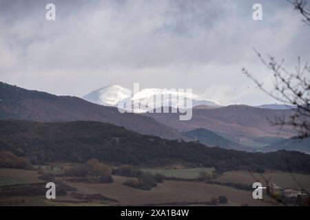 In autunno, la catena montuosa Cantabrica presenta un impressionante scenario naturale, con vette innevate che si innalzano sopra i vivaci prati verdi. Foto Stock